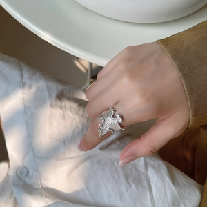 Close-up of minimalist silver wave ring with unique lava texture on a model's finger
