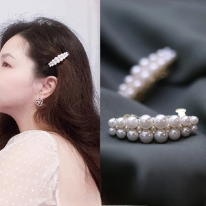 Detail of elegant white faux pearl hair clip with gold metal base and side view of model