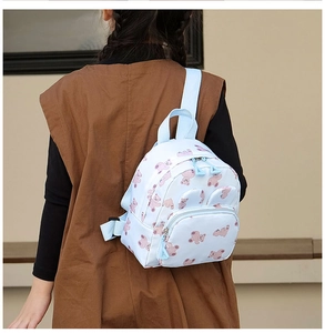 Rear view of a light blue children's backpack with bear patterns on a model girl
