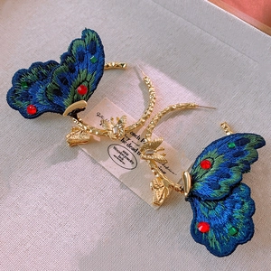 Detail of vintage embroidered butterfly earrings with crystals on golden hoops