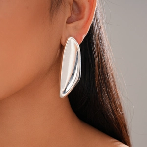 Close-up of a silver irregular geometric earring with a liquid sculpture design on ear