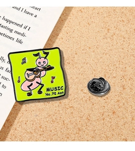 Detail of pink cartoon ant playing guitar on green metal badge with MUSIC text
