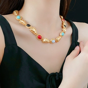 Detailed close-up of a vintage gold necklace featuring colorful gemstone shell elements