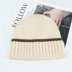Winter striped knit beanie in cream and coffee tones on a minimalist magazine