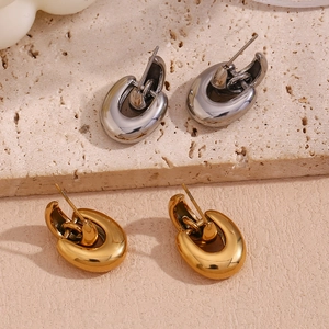 Polished U-shaped chunky gold and silver earrings on a textured stone surface