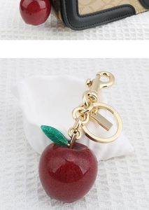 Detail of red glitter apple keychain with green leaf and gold metal link on shell
