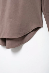 Detailaufnahme der präzisen Nähte und Stoffstruktur einer braungrauen Damenbluse