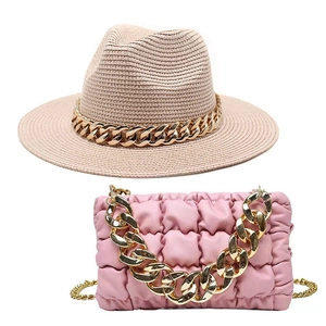 Detail of beige straw fedora hat and pink quilted bag with chunky gold chain accents