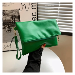 Dettaglio di una pochette in pelle verde brillante con zip dorata e cinturino da polso