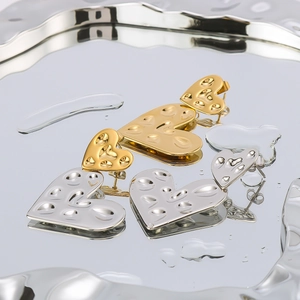 Dual heart pendant earrings in 18K gold and silver finish on artistic water ripple surface