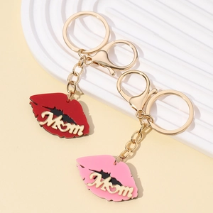 Pink and red lip-shaped metal keychains with golden Mom lettering on a neutral surface