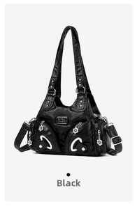 Macro view of black PU leather bag showing silver metal rings, studs and floral charm