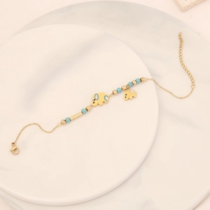 Detail of turquoise beads and golden elephant charm on a minimalist stainless steel bracelet
