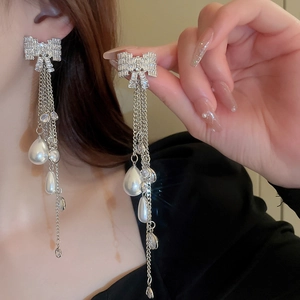 Detail of silver bow earrings with long diamond tassels and white waterdrop pearls