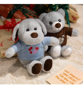 Ours et chiot en peluche avec pulls tricotés sur tapis avec boîtes cadeaux