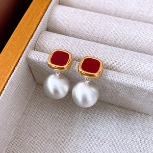 Macro shot of matte acetate red square stud with textured pearl drop earring detail