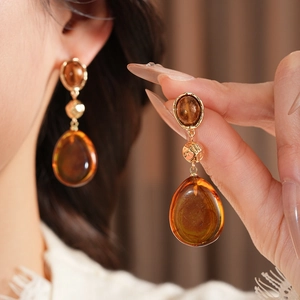 Macro detail of amber resin teardrop earrings with vintage gold metal accents