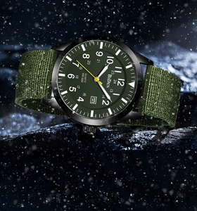 Detailed view of military quartz watch with army green nylon strap on snowy rock background