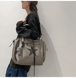 Detail of grey water-resistant tote bag with star print and checkerboard pendant charm