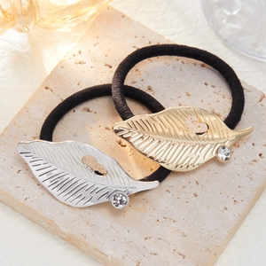 Detail of gold and silver metal leaf charms with small crystals on black elastic hair ties