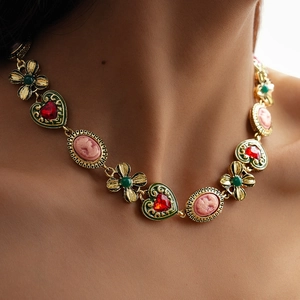 Detail of vintage cameo necklace with red heart gemstone and floral enamel pendant