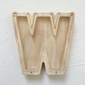 Macro detail of oak wood letter W piggy bank with clear acrylic panel and gold screws