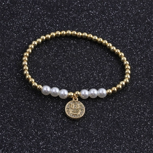 Macro detail of gold-plated pearl bracelet featuring a crystal-encrusted smiley face charm