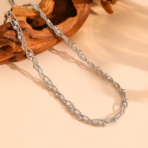 Gros plan d'un collier multicouche argenté avec perles sur bois flotté rustique