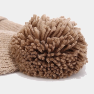 Close-up of camel knit pom-pom detail on winter hat showing high-quality wool texture