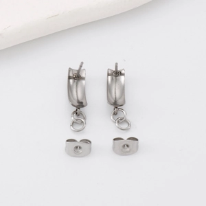 Gros plan de boucles d'oreilles en acier argenté avec petits pendentifs cercles sur fond blanc