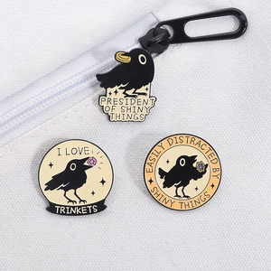 Close-up of raven enamel pins with shiny gems on white canvas bag detail