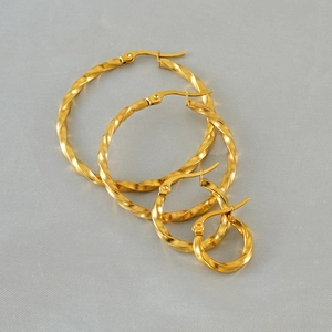 Three pairs of golden stainless steel twisted hoop earrings in graduated sizes on grey