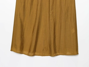 Close-up of pleated ginger fabric showing vertical texture and refined hem stitching