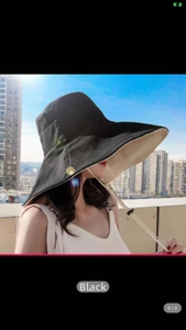 Side view of a large brim black sun hat with adjustable white chin strap outdoors