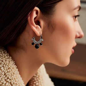 Close-up of vintage C-shaped silver spiral earrings with black beads on model