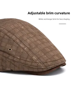 Detail of a brown plaid newsboy cap with flexible wide brim and metallic eyelet vents
