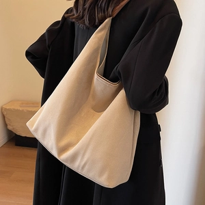 Large beige matte leather hobo bucket bag shown on a model for a stylish casual look