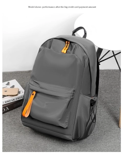 Detail view of water-resistant gray backpack featuring orange zipper accents and side pocket