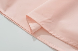 Detail view of pink dress showing fine plain weave fabric and double-stitched hem finish