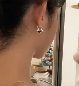 Vista dettagliata di un orecchino a stella in argento indossato da una modella in casa