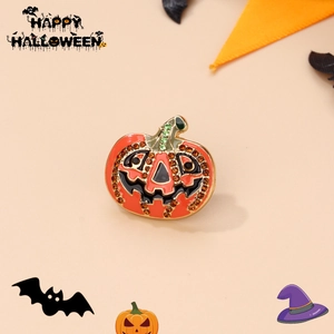 Detail of Halloween pumpkin brooch with orange enamel and green rhinestone accents