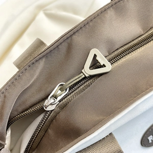 Coffee nylon tote bag with high-quality golden zipper detail and close-up fabric texture