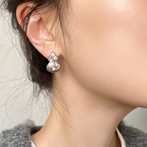 Detailed close-up of a silver gourd earring with a pearl inlay worn by a model