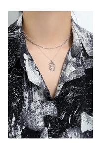 Macro detail of silver tulip pendant necklace with double layered chain on neck