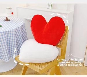 Detail of red and white heart-shaped plush pillows on a vintage wicker chair decor