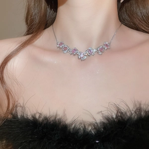 Close-up of a silver necklace with pink gems and zircons in a floral design on a model