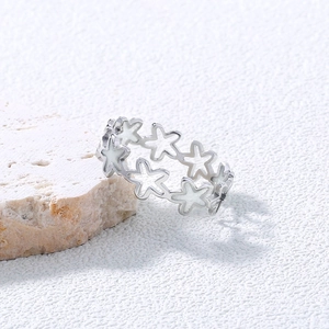 Polished 304 stainless steel ring with hollow star design on a white textured stone