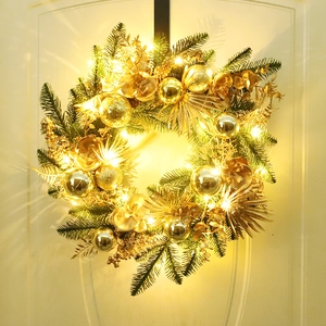 Golden Christmas wreath with green PE pine needles and warm LED lights on a white door