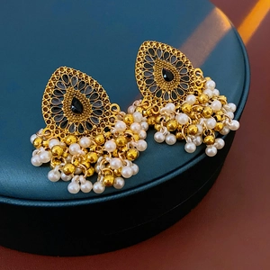 Détail de boucles d'oreilles vintage dorées avec pierre noire et pompons de perles blanches