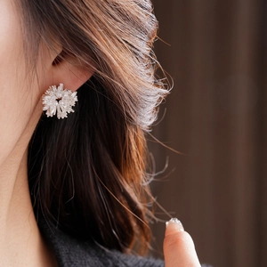Gros plan d'une boucle d'oreille flocon en perle et zircone portée sur l'oreille du mannequin